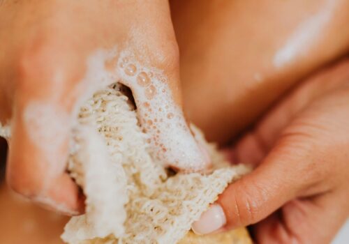 Close-up of a woman using a natural sponge and soap for exfoliation, embracing relaxation and body care.